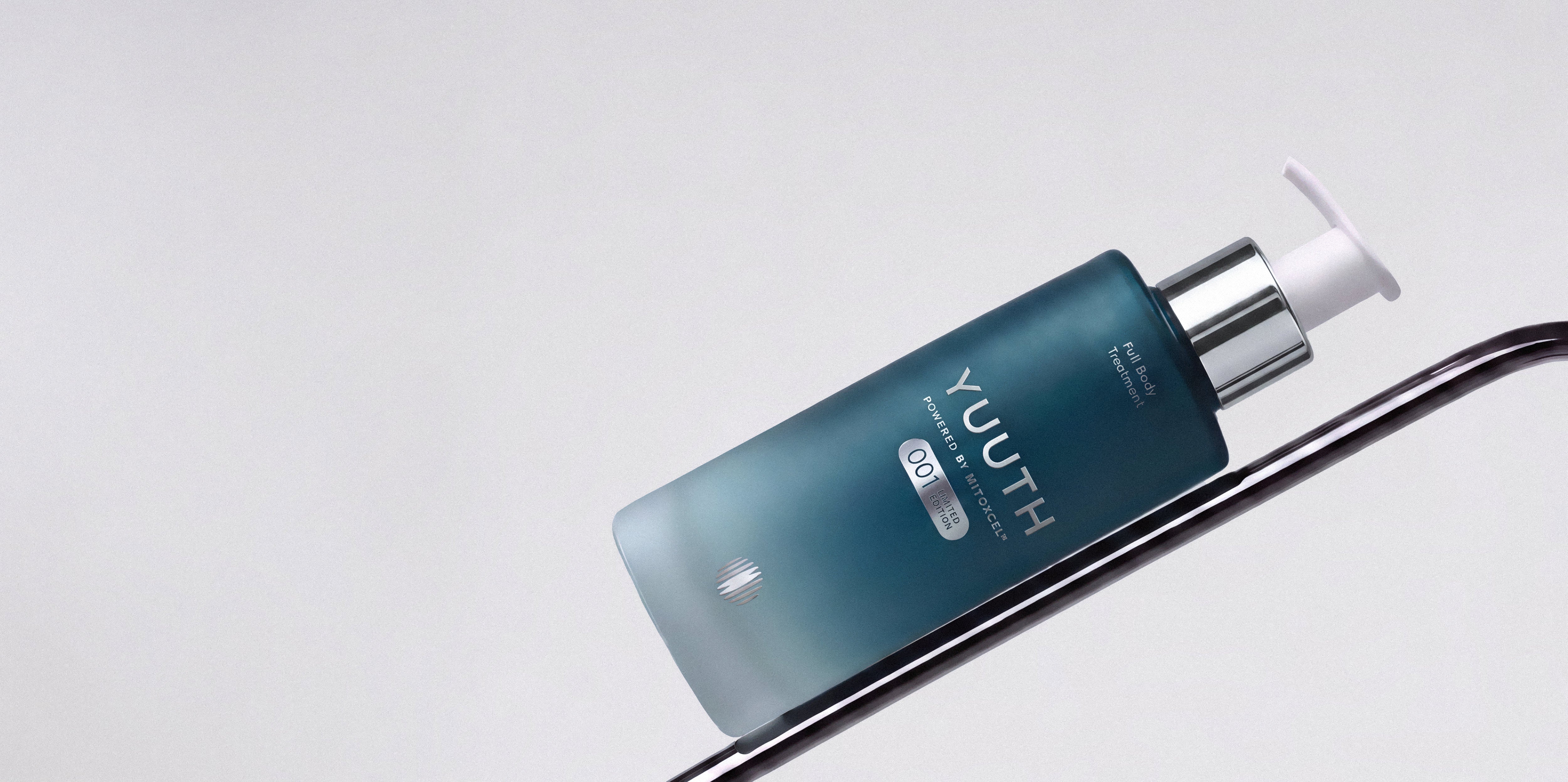 The Full Body Treatment bottle resting on a dark curved wire against a pale background