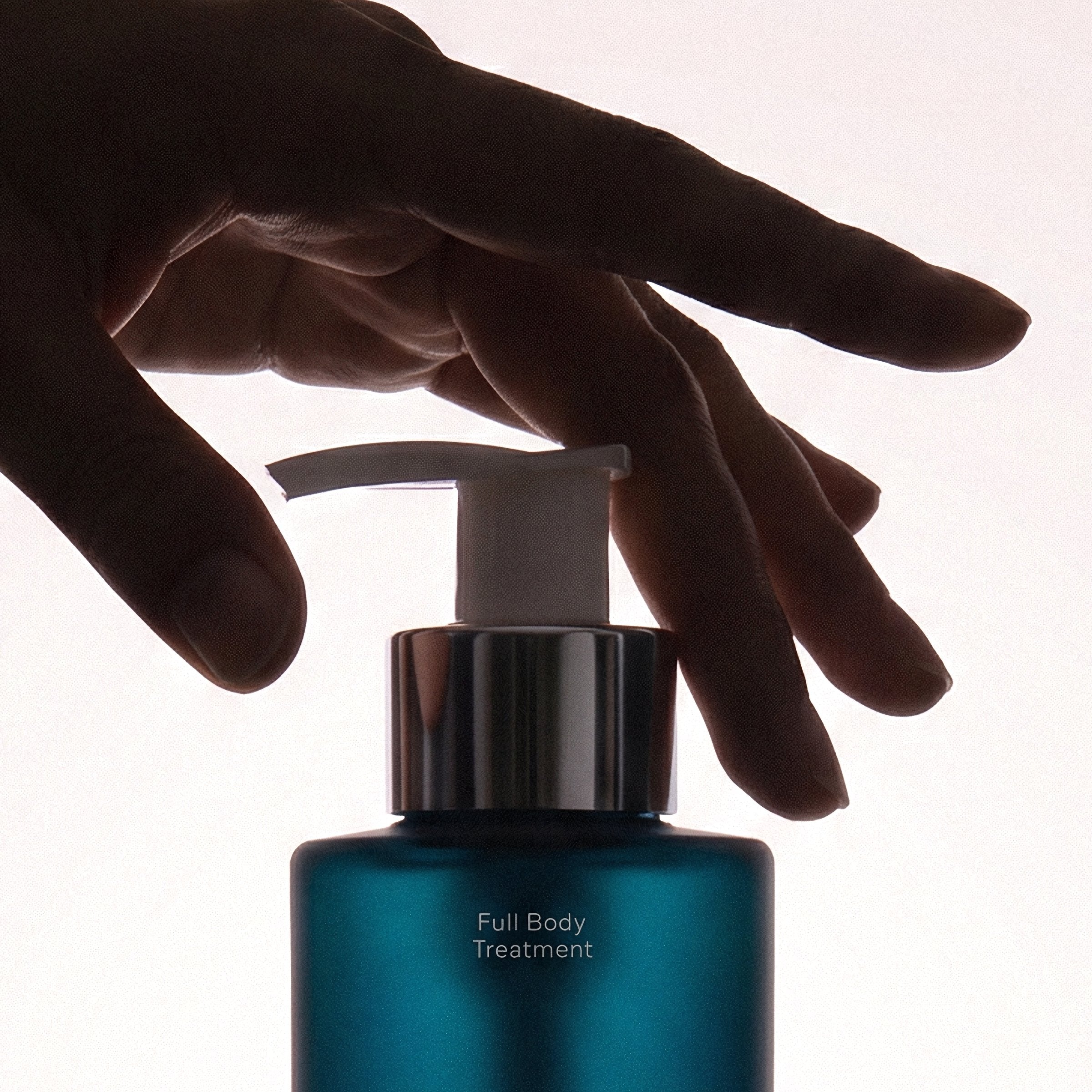 A hand reaching for the pump on the Full Body Treatment bottle